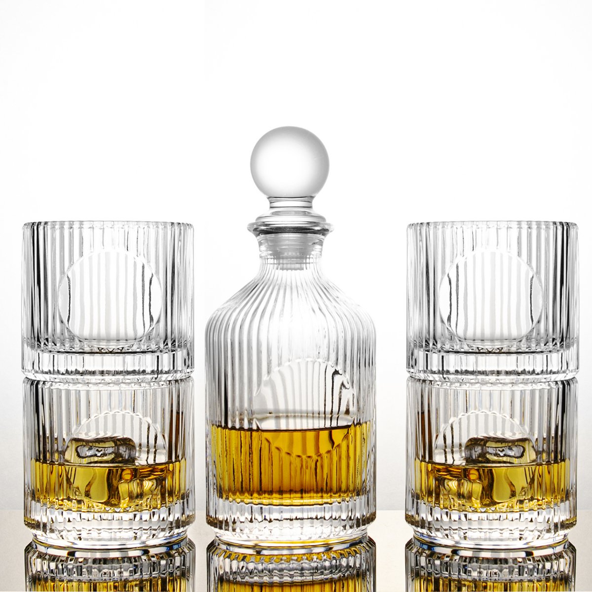 Crystal decanter with two glasses filled with a yellow liquid on a white background
