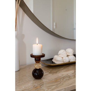 Candle in a decorative holder on a marble surface with a mirror in the background