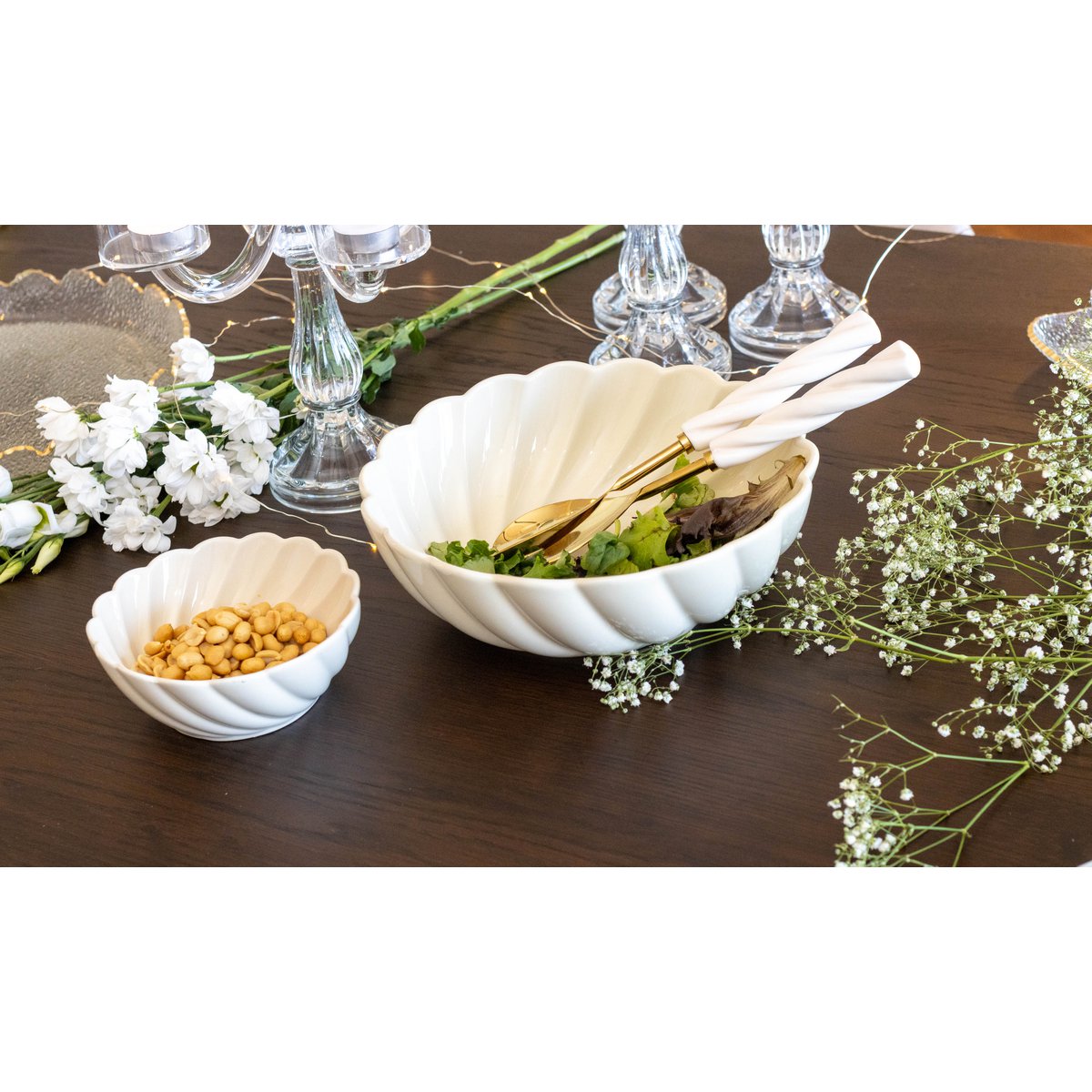 Zwei weiße Keramikschalen auf einem Holztisch mit Blumen und Gläsern im Hintergrund
