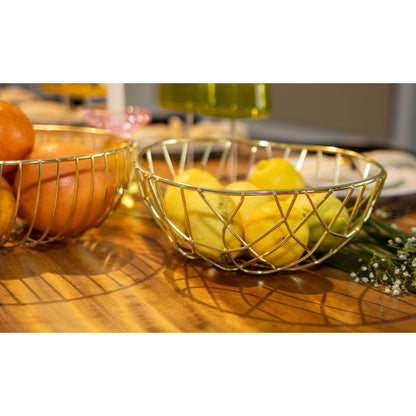 Gold wire fruit bowls with oranges and lemons on a wooden surface
