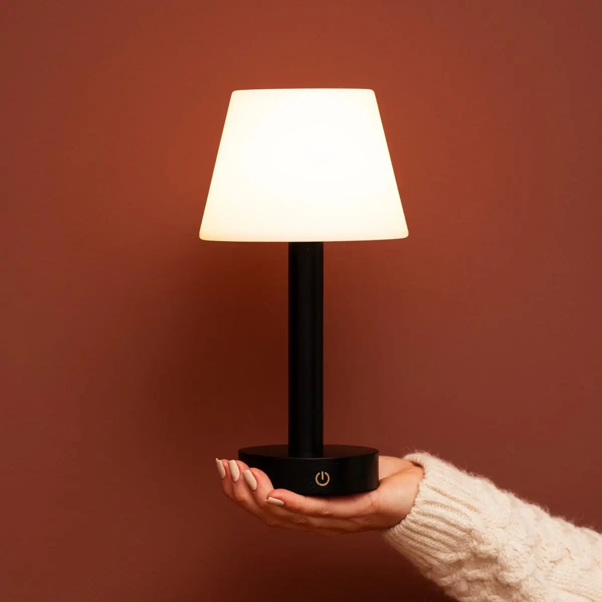 Zoë Black portable lamp shown being held by hand indoors