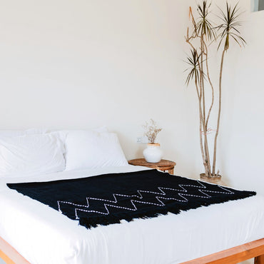 Handwoven Black Cotton blanket with Zigzag Pattern and Fringes on bed